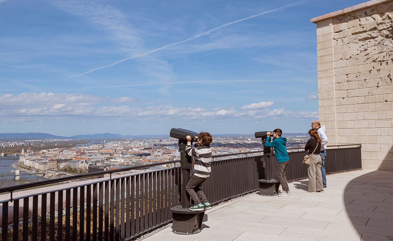 A Citadella panorámateraszán látogatók távcsövekkel tekintik meg Budapest városképét és a Dunára nyíló kilátást